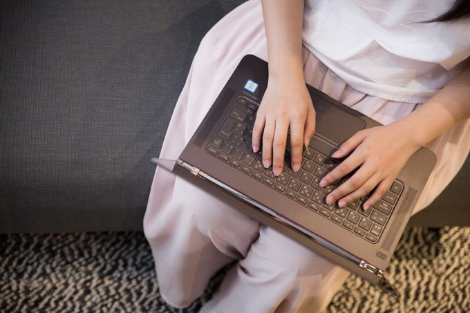 膝の上でノートパソコンを操作する女性